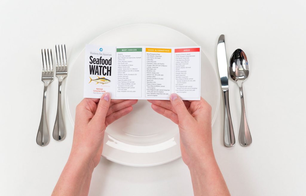 A diner holds a pocket guide to sustainable seafood from Monterey Bay Aquarium Seafood Watch.